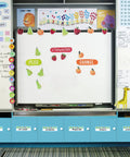 Classroom whiteboard with fruit illustrations and vocabulary words, surrounded by educational materials and colorful decorations.
