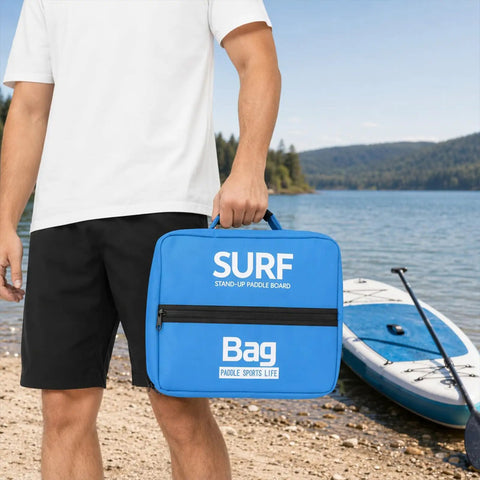 Man holding Insulated Cooling Pack for Seaside Adventures and Water Sports next to paddleboard on a sunny beach.