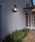 JUDYSSY Solar Flood Lights Led Solar Floodlight mounted on a wall, outdoor waterproof IP65, illuminating garden pathway.