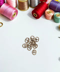 Miniature Doll Belt Buckles Set 150 Pieces Alloy Locking Buckles In Silver, Gunmetal, And Antique Copper For Do It Yourself Doll Clothes, Crafts, And Mini Sewing Projects surrounded by colorful sewing thread.