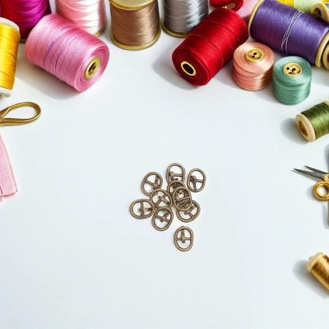 Miniature Doll Belt Buckles Set 150 Pieces Alloy Locking Buckles In Silver, Gunmetal, And Antique Copper For Do It Yourself Doll Clothes, Crafts, And Mini Sewing Projects surrounded by colorful sewing thread.