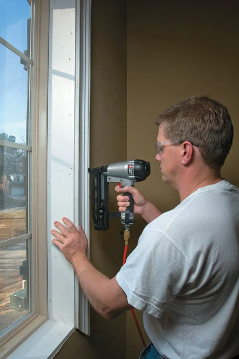 Person using 16-Gauge Straight Finish Nailer Kit With Tool-Free Depth-Of-Drive Adjustment on a window frame