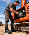 Man in Steel Toe Work Boots For Men Waterproof Non Slip Industrial Construction Shoes Black Built For The Job Tough As Nails Outdoor Safety Footwear With Water Repellent Upper And Rugged Wear Resistant Patch For Long Lasting Protection next to excavator