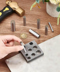 Hand using Heavy Duty Carbon Steel Disc Cutter Set for jewelry making with six cutting punches seen on a wooden table.