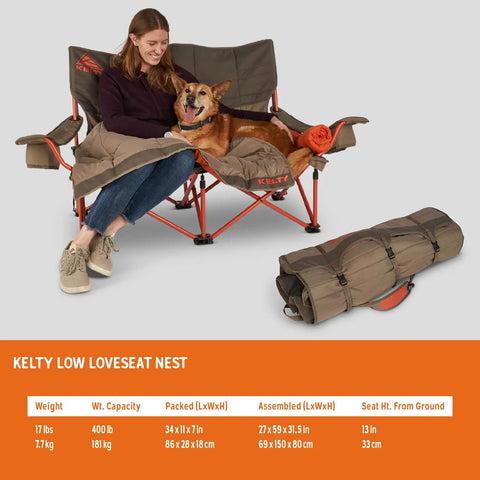 Woman and dog on two person camping chair with removable blankets low to the ground loveseat nest cozy cuddle recline insulated beverage holders roll tote storage all in one camp couch for couples 2024 Beluga.