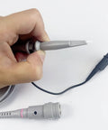 Hand holding 100MHz Oscilloscope Probe Kit With BNC Clip Probes Attenuation Adjustable 1x Or 10x, showing detachable hook tip.