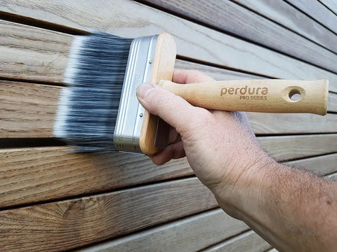 Hand using Go To Rapid Stain Deck Brush Applicator 5 Inch for fast staining on wood surface with oil and water-based coatings.