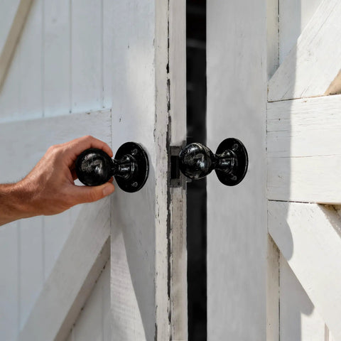 Hand using Built Tough Heavy Duty Matte Black Barn Door Pull Handle Solid Zinc Alloy Ring Knob on white double doors.