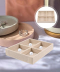 No Sweat Beige Velvet Jewelry Tray With Four Grid Compartments For Quick Sorting Rings Earrings And Bracelets Easy Drawer Insert Organizer on a table with jewelry.
