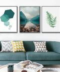 Modern living room with green sofa, geometric and nature-themed framed artwork on white wall