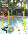 Drone Racing Obstacle Course Kit for Beginners and Pros set up on an outdoor basketball court with two drones flying through hoops.