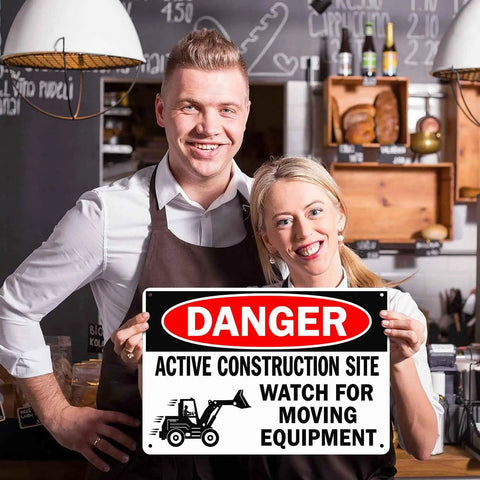 Couple holding Heads Up Construction Site Sign Aluminum 8x12 Inch Watch For Moving Equipment Warning Sign indoors