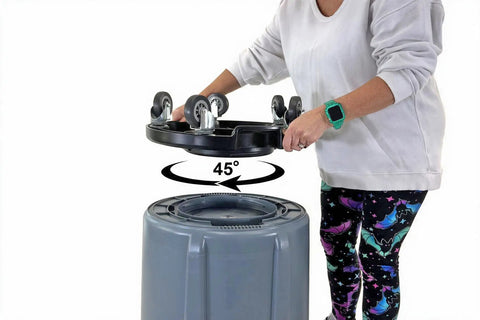 Heavy Duty Trash Can Dolly With Five Casters And Foot Stabilizer Plastic Utility Cart That Fits 20 To 55 Gallon Brute Containers Supports Up To 460 Lb Durable Black Finish For Easy Transport, shown tilted 45 degrees over a trash can