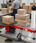 Heavy Duty Electric Stretch Wrap Dispenser Packing Station For Super Fast And Zero Sweat Box Wrapping With 220V Wall Setup And Rock Solid Semi Automatic 30 Rpm Motor Assembly on packing table with boxes.
