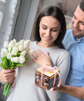 Front view: smiling couple with white tulips bouquet and a small gift box tied with pink ribbon.