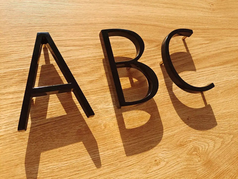 5 Inch Modern Floating Address Numbers For Houses In Rust Proof Zinc Alloy With A High Gloss Black Finish Dope Easy To Install Outdoor House Numbers Durable Weather Resistant Address Plaque For Home Exterior showing letters A, B, C on wood surface
