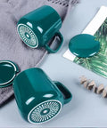 Skip The Lukewarm Sip With This Smart Electric Coffee Mug Warmer Set featuring teal ceramic mugs with decorative lids.