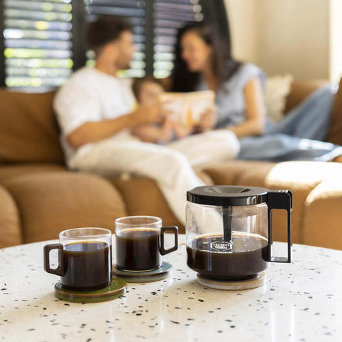 1.25L Glass Carafe for KBG Brewers, Clear Black Version, on table with cups in modern living room setting.
