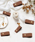 12 Pack Brown Leather Drawer Pulls With Single Hole Mount for Kitchen Cabinets and Furniture, shown on a table with decor