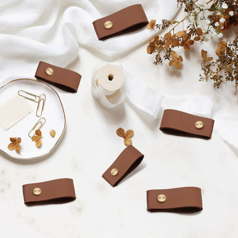 12 Pack Brown Leather Drawer Pulls With Single Hole Mount for Kitchen Cabinets and Furniture, shown on a table with decor