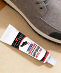 Tube of All Purpose Quick Dry Shoe Glue For Sneakers Boots And Sandals, shown next to a gray sneaker, on a beige surface.