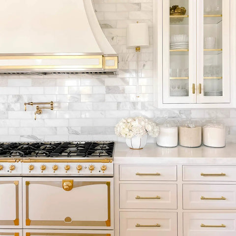 White kitchen with a vintage stove and brass accents, featuring Six Pack Antique Brass Drawer Pulls For Kitchen Cabinets And Dressers.