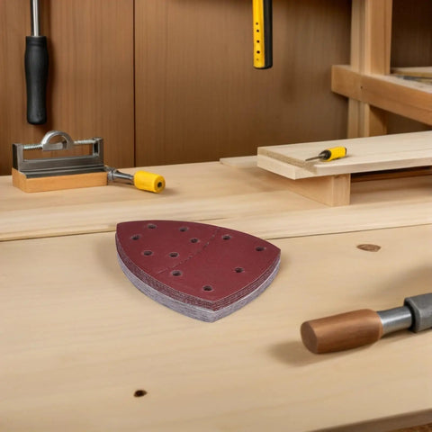 Merryhappy 60pcs Triangle Mouse Detail Sander Sandpaper Sheets with 11-Hole Hook and Loop Backing on a woodworking bench.