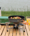 Portable Butane Gas Camping Stove With 7500 BTU Output Ultra Compact Folding Design With Carry Bag For Backpacking RV Trips Picnics And Outdoor Or Indoor Cooking Green on wooden table.