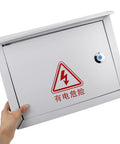 Front view of Weatherproof Metal Electrical Junction Box Outdoor Enclosure 300x400x160mm held by person showing lock and warning sign.