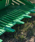 Close-up of 72 Inch Grade 50 Skeleton Rock Grapple Bucket for Tractors, showing open tine design and replaceable teeth on grass.