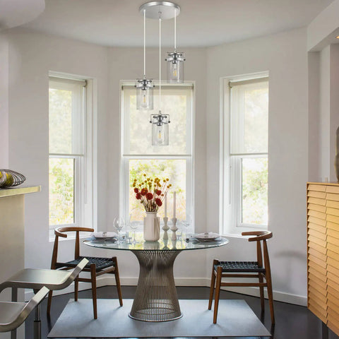 Three Light Glass Pendant Light With Brushed Nickel Finish And Clear Glass Shades Adjustable Cord Cool Farmhouse Ceiling Fixture shown over a dining table.