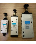 Three manually operated two five solenoid pneumatic valves S25 Series on wood background, used for hydraulic control.