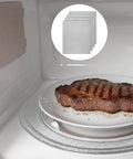 4 Pc Waveguide Cover Replacement Kit With Scissors, 150Mm By 120Mm Mica Plates Sheets shown in a microwave next to cooking steak.