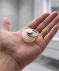White Drain Stopper with Stainless Steel Ring, Silicone Seal Plug held in hand, showcasing its small size and practical design.