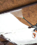 Applying Expandable Polyurethane Spray Foam Insulation for Superior Heat And Sound Control under a ceiling beam.