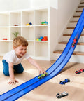 Child playing with 15 Ft Flexible Race Track Set With Two Lane Track And 6 Toy Cars For Kids, blue PVC track running down stairs