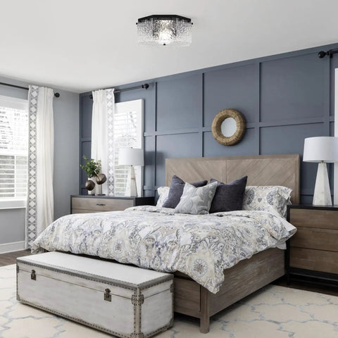 Modern bedroom with blue accent wall and patterned bedding, featuring a flush mount ceiling light.