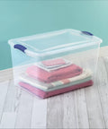 Blue 66 Quart Clear Storage Bin with Latching Lid for Easy Grip Heavy Loads Stackable Plastic Container Organize Clothing Boots and Seasonal Gear with folded blankets inside.