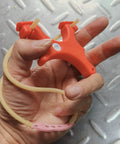 Hand holding Ultra Compact Mini Slingshot With Flat And Round Bands In Red Nylon Fiber, Ambidextrous And Pocket Sized For On The Go