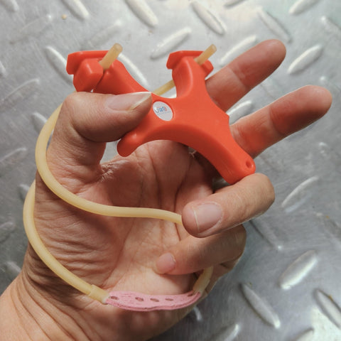 Hand holding Ultra Compact Mini Slingshot With Flat And Round Bands In Red Nylon Fiber, Ambidextrous And Pocket Sized For On The Go