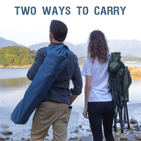 Rear view of two people carrying Oversized Folding High Back Lawn Chair for Adults With Cup Holder and Carrying Strap by a lake.