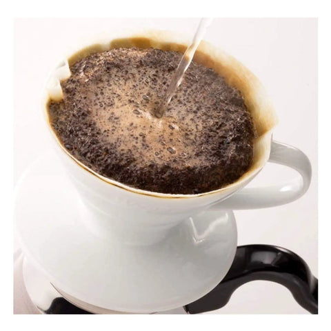 Pouring water over coffee grounds in a V60 Size 02 White Coffee Filter, showing the brewing process in a ceramic dripper.