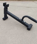 Heavy Duty Barbell Plate Lifter And Plate Change Jack with secure curved handle on concrete surface.