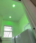 Smart Downlight Retrofit Kit With SuperColor Technology, 800 Lumen, 90 CRI installed in a recessed ceiling, glowing green in a laundry room