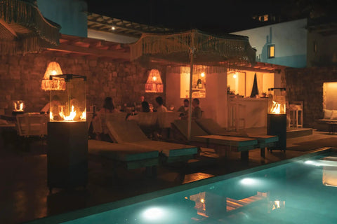 Smokeless 360 Degree Propane Patio Heater, 41,000 BTU, 59 Inch Freestanding Glass Tower On Wheels at night by poolside