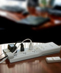 8 Outlet Conserve Switch Surge Protector With Remote, 4ft Cord, White Power Strip For Computer Desk Setup shown on table with devices.
