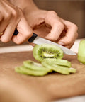 3.25 Inch Paring Knife With Straight Edge Spear Point slicing kiwi on cutting board