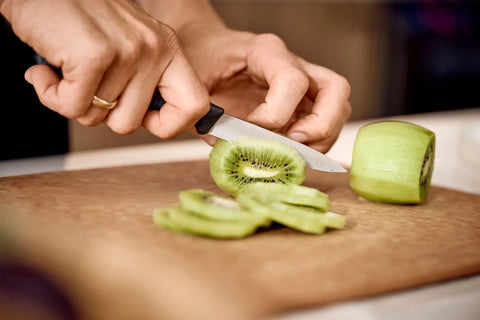 3.25 Inch Paring Knife With Straight Edge Spear Point slicing kiwi on cutting board