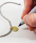 Gold Tyvek Self Adhesive Dumbbell Jewelry Price Tags 1000 Pack being used on a necklace, tear resistant and easy peel.