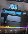47 Inch Gaming Desk With Power Outlets And LED Lights Reversible Computer Desk With Five Fabric Storage Drawers Monitor Stand For Home Office And Study Setup Vibe Black displaying LED lights and storage drawers.
